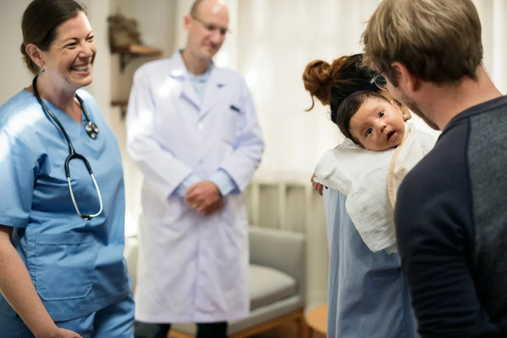 photo - doctor and delivery and labor nurse congratulating a couple with their newborn