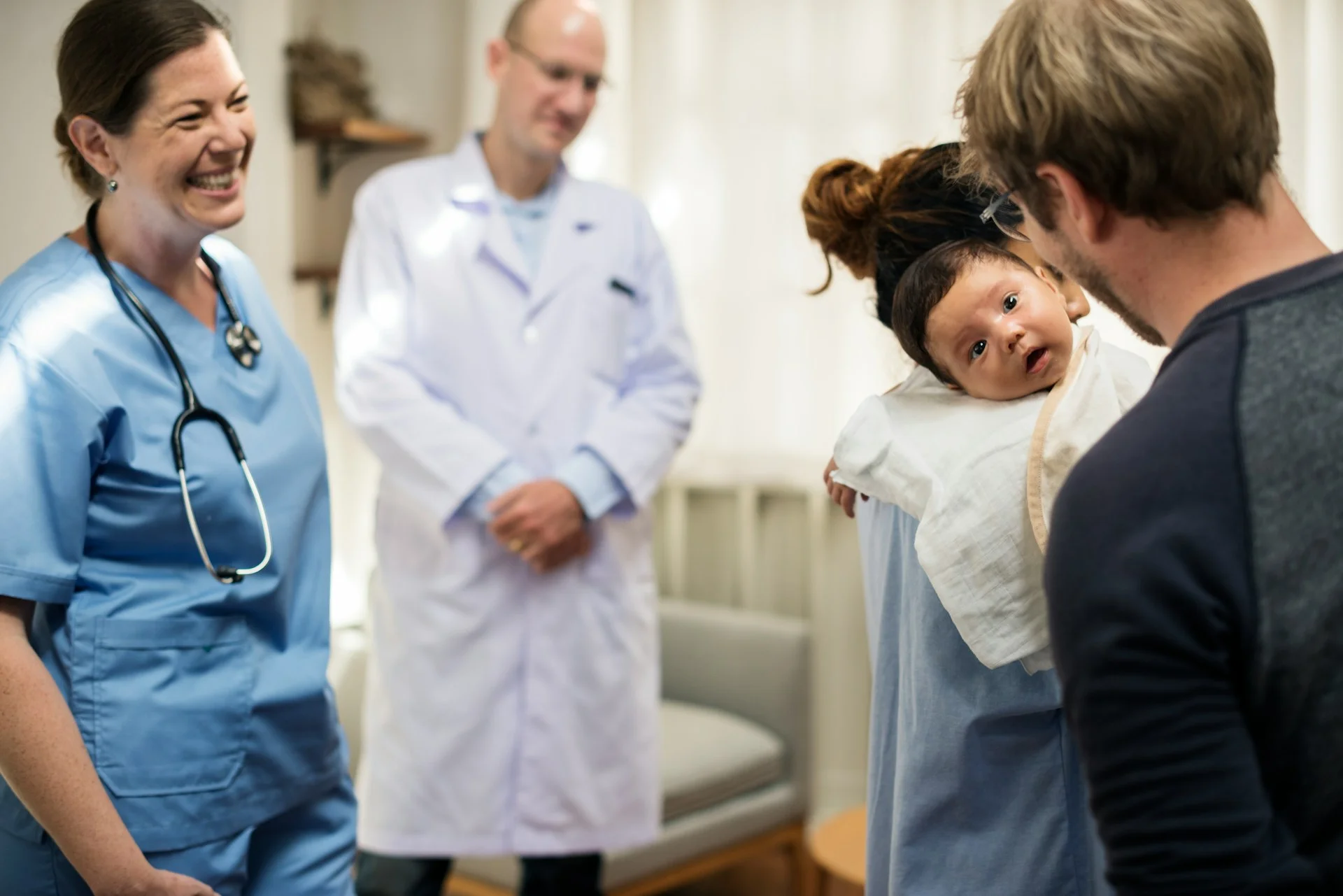 photo - doctor and delivery and labor nurse congratulating a couple with their newborn